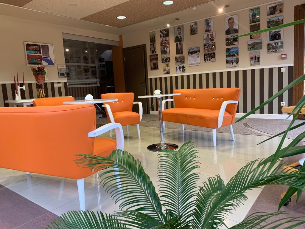 una sala de espera con sillas naranjas y una planta en Broliu Vila, en Druskininkai
