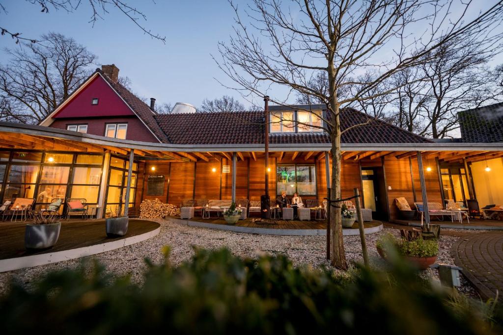 een groot houten huis met mensen in een tuin bij Droste's Herberg in Tubbergen