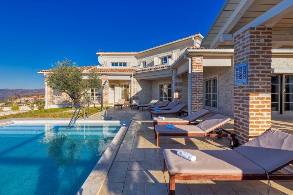 a house with a swimming pool with lounge chairs next to it at Villa Star in Vižinada