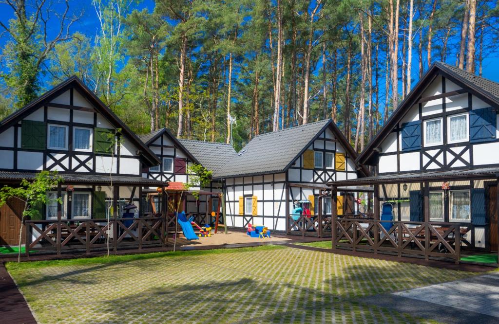 a house with a playground in the woods at Domki Tutti Frutti in Pobierowo