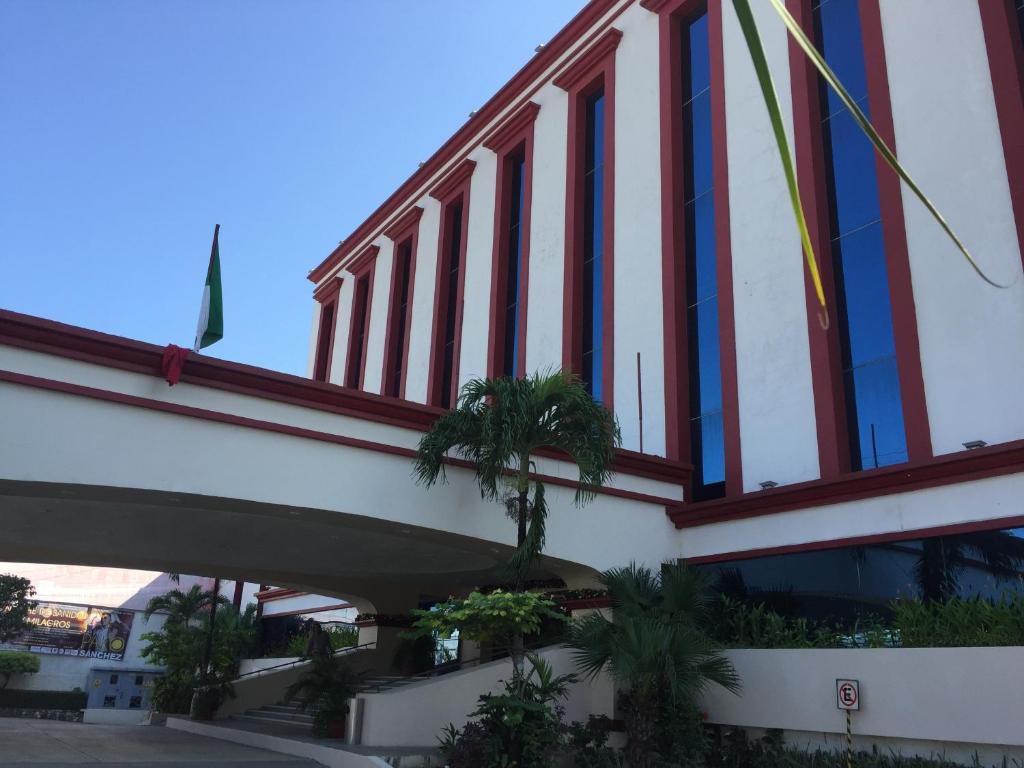 a building with red and white windows and palm trees at Hotel Maya Tabasco in Villahermosa