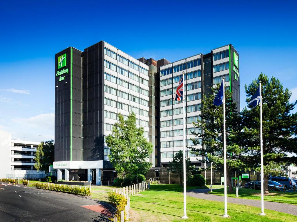 un edificio de hotel con banderas frente a una calle en Holiday Inn - Glasgow Airport, an IHG Hotel, en Paisley