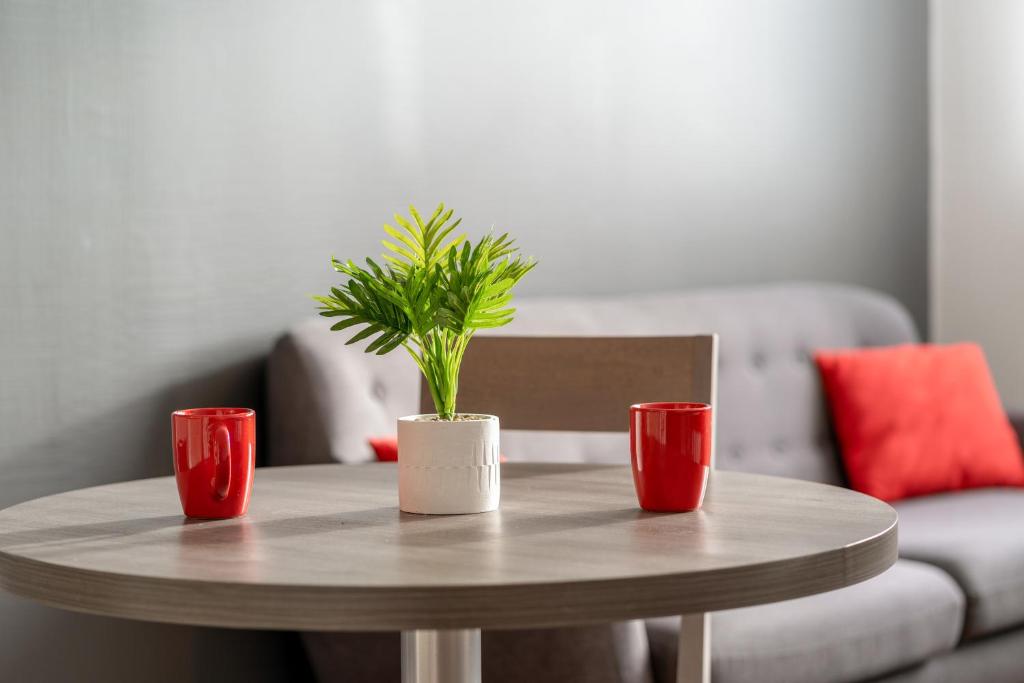 a table with two red cups and a potted plant on it at Zenitude Hôtel-Résidences Nantes Métropole in Nantes