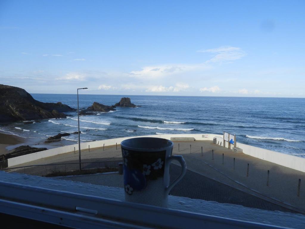 eine Kaffeetasse auf einem Balkon mit Meerblick in der Unterkunft Apartamento Sto Estevão in Zambujeira do Mar