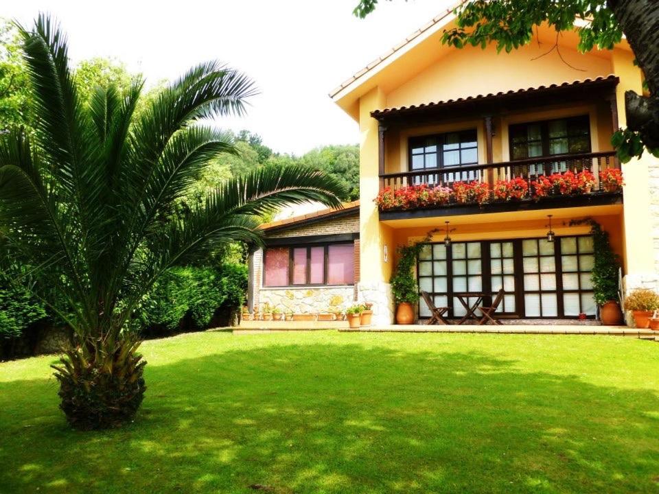 uma casa com uma palmeira em frente a um quintal em Las endrinas em Llanes