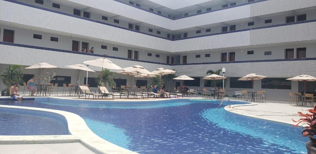 Belo Jardim的住宿－Hotel Asa Branca，一个带桌子和遮阳伞的酒店游泳池