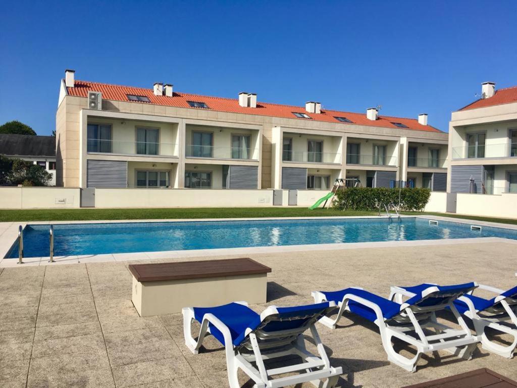 una piscina con sillas, una mesa y un edificio en SeaHorse House, en Esposende