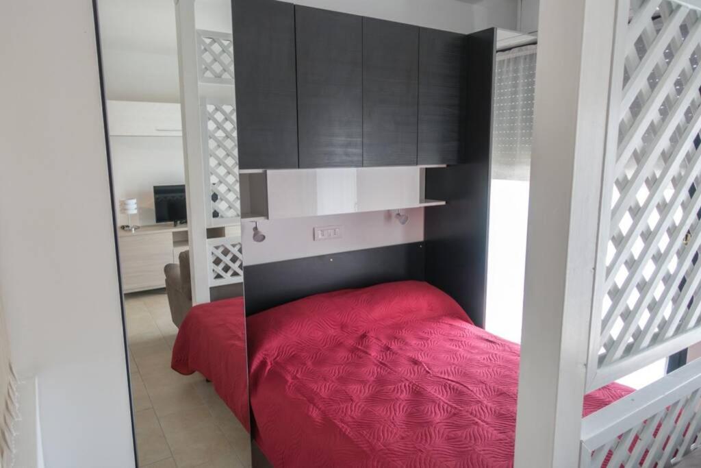 sypialnia z czerwonym łóżkiem i czarnymi szafkami w obiekcie Apartment Victoria, cozy studio flat near Leonardo Academy w mieście Sesto Calende