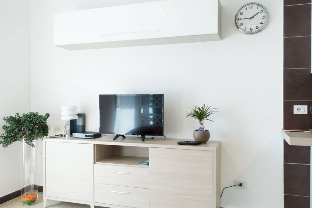 białe biurko z telewizorem i zegarem na ścianie w obiekcie Apartment Victoria, cozy studio flat near Leonardo Academy w mieście Sesto Calende