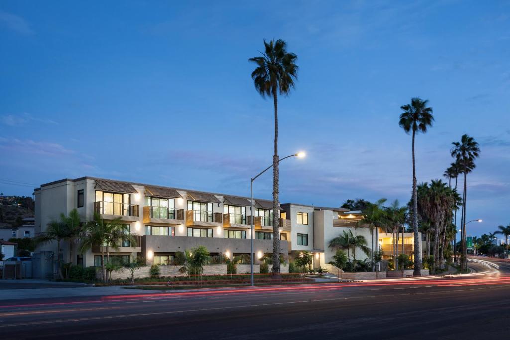 een gebouw met palmbomen voor een straat bij Holiday Inn Express and Suites La Jolla - Windansea Beach, and IHG Hotel in San Diego