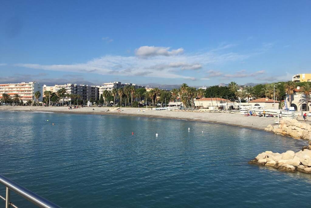 a body of water with a beach and buildings at Charmant appartement bord de mer, Plage in Cagnes-sur-Mer