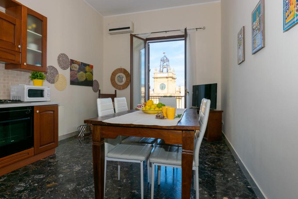una cucina con tavolo, sedie e forno a microonde di Il Mosaico Family Apartments a Mazara del Vallo