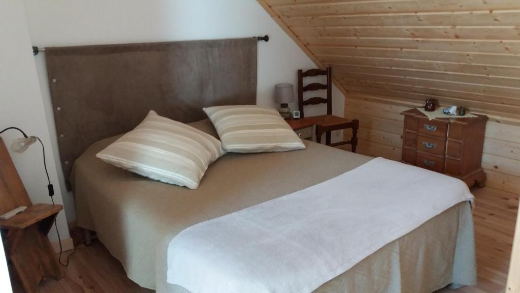 una camera da letto con letto, lenzuola e cuscini bianchi di Apibus Domus - Chris et Stèph a Guillaumes