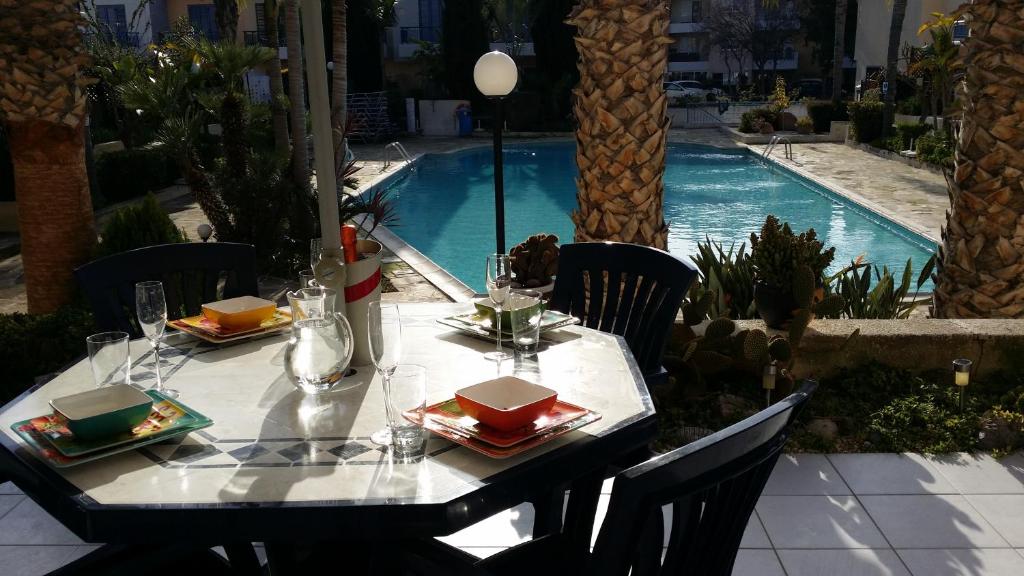 een tafel met borden eten naast een zwembad bij Maya's Apartment - Complimentary Paphos Airport Transport in Paphos City