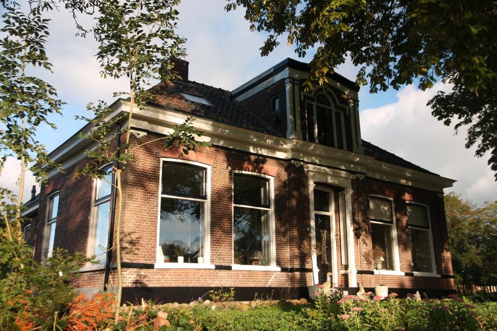una vieja casa de ladrillo con una torre encima en Onder De Boom, en Gerkesklooster