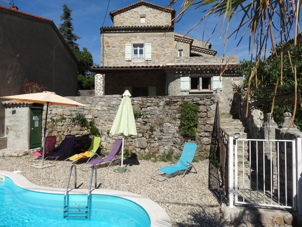 uma casa com uma piscina e cadeiras e um guarda-sol em Gites les Eaux Claires em Saint-Paul-le-Jeune