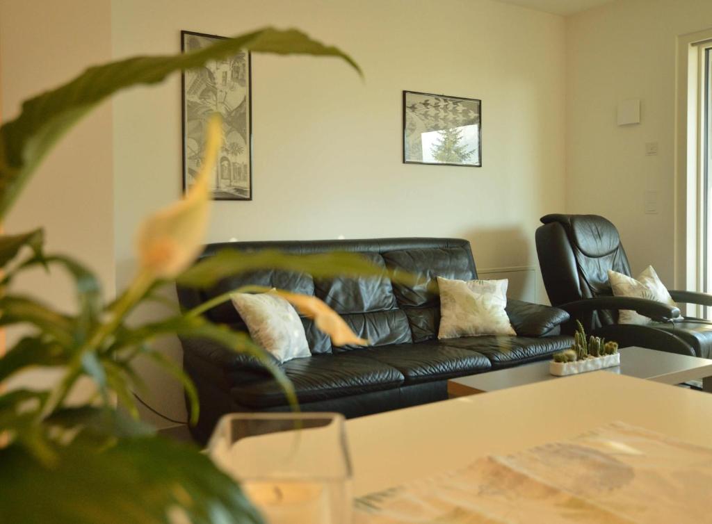 uma sala de estar com um sofá de couro preto e uma mesa em Family Apartment Julia em Termeno