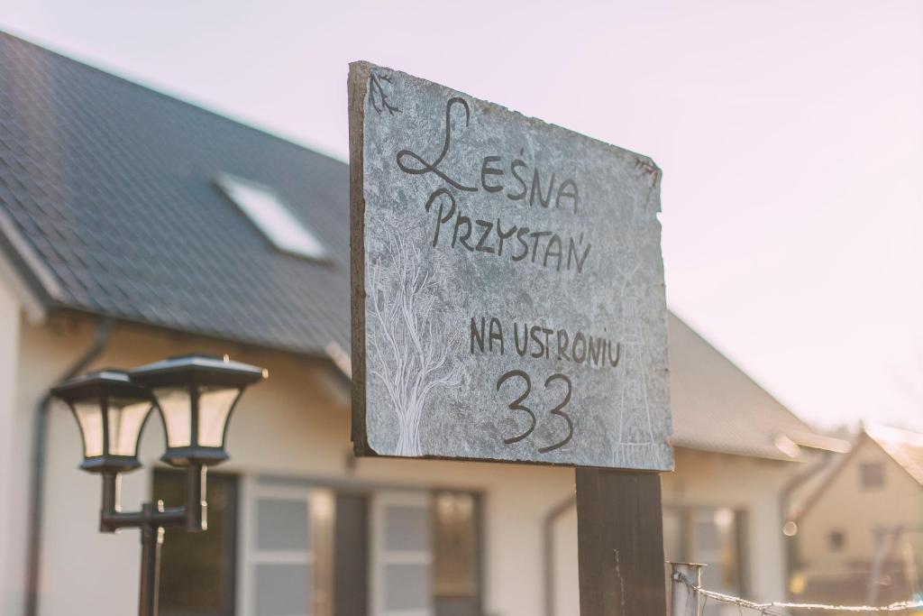a sign in front of a building with a house at Leśna Przystań in Sasino