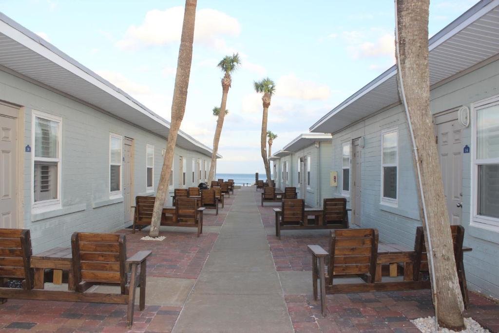 Shoreline Suites & Cabana Cottages – Beachfront في دايتونا بيتش: صف من البيوت فيها مقاعد والنخيل