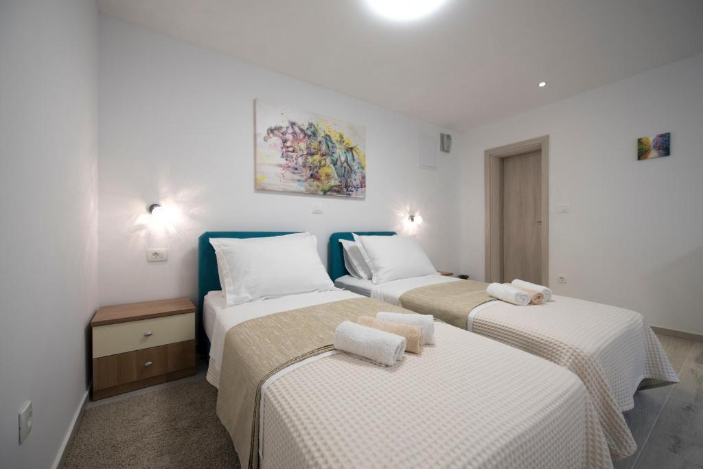 Duas camas num quarto com paredes brancas em Apartments Maraton em Split