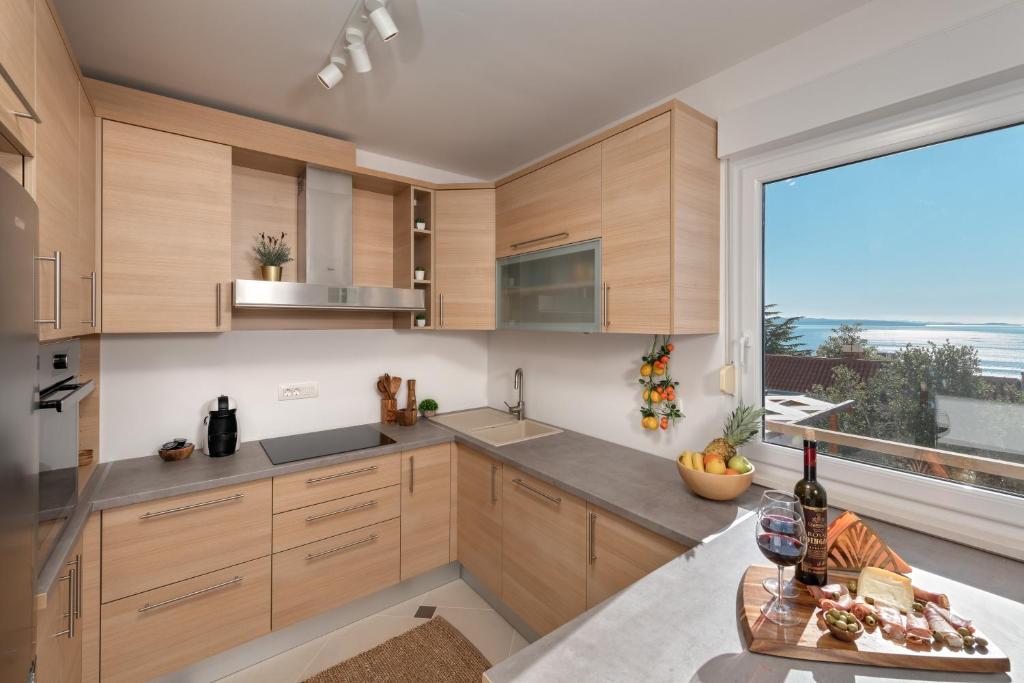 a kitchen with wooden cabinets and a large window at Sun Spalato Hills in Split