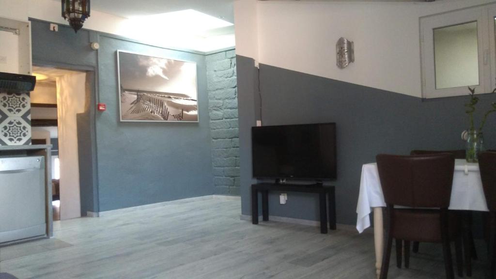 sala de estar con TV y mesa con sillas en Mauguio Center Hôtel en Mauguio