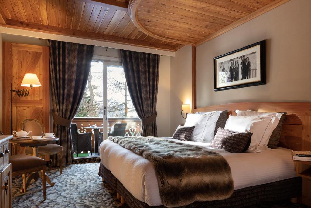 una habitación de hotel con una cama grande y una mesa en Hôtel Chalet Mounier en Les Deux Alpes