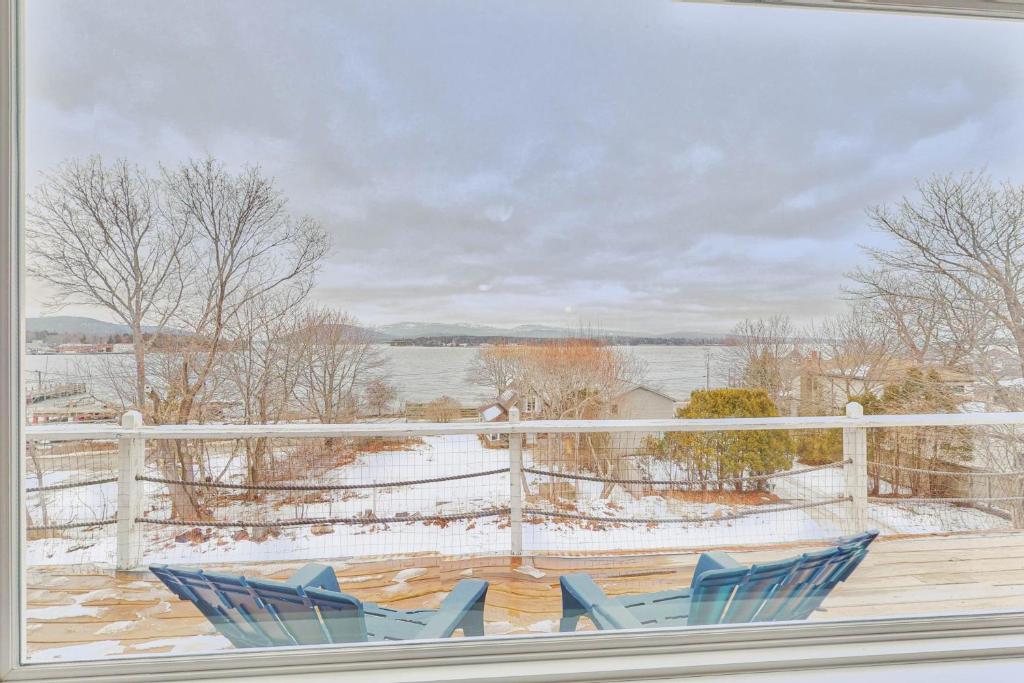 two blue chairs on a deck with snow on the ground at Manset Village Overlook in Southwest Harbor