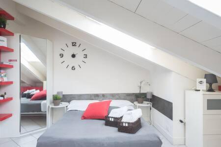 1 dormitorio con 1 cama con reloj en la pared en Welcome Brescia Apartments - Volta en Brescia