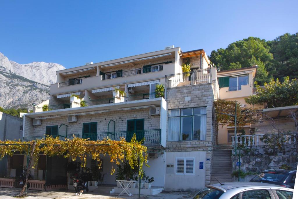 an apartment building in front of a mountain at VILLA MILENKA - Apartmani Gorana in Tučepi