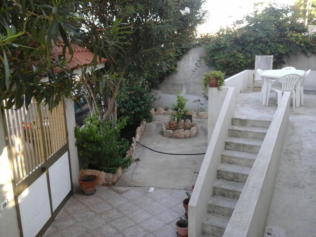 a patio with stairs and a table and trees at Appartamento con giardino in Lampedusa