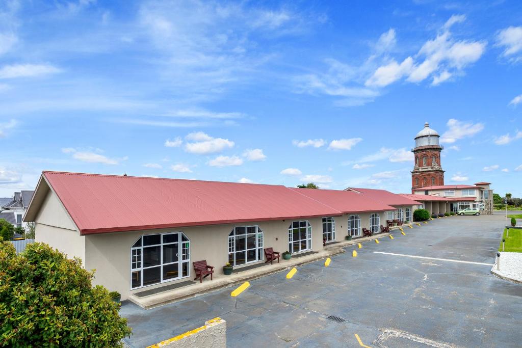 un edificio con una torre de reloj y un aparcamiento en Tower Lodge Motel, en Invercargill