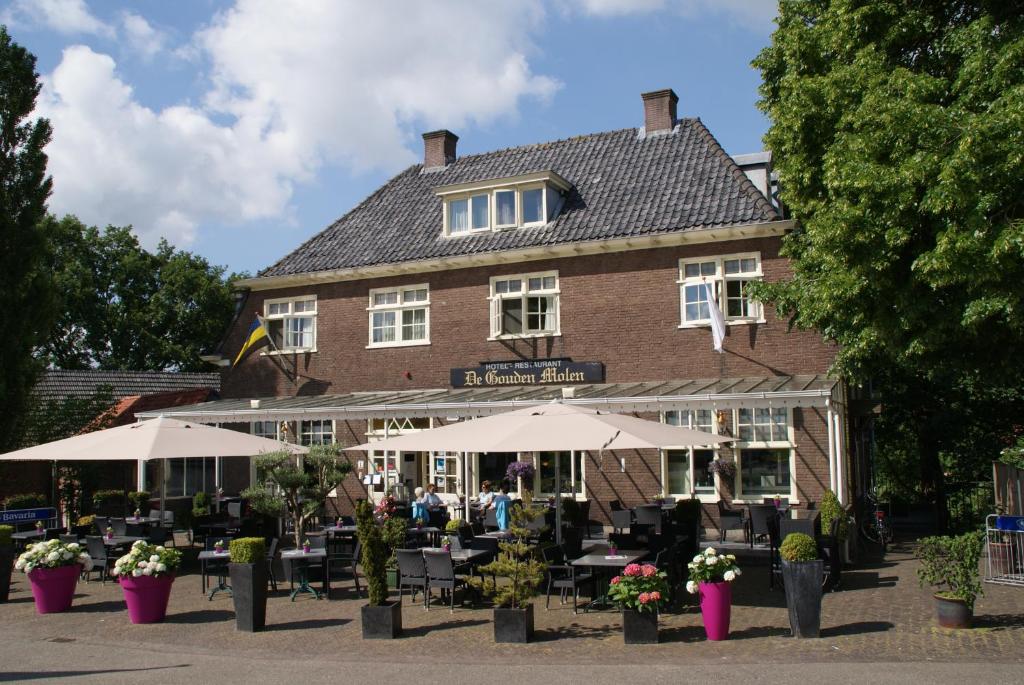 a restaurant with tables and umbrellas in front of a building at De Gouden Molen in Rossum