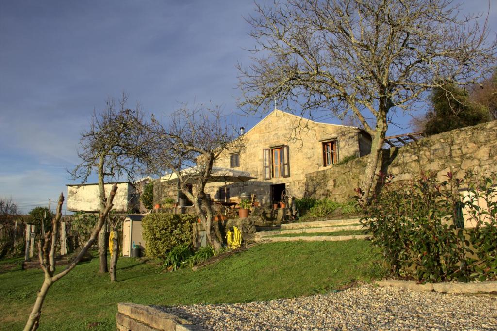 una casa de piedra con una pared de piedra y árboles en Vinosobroso Casa Rural en Mondariz