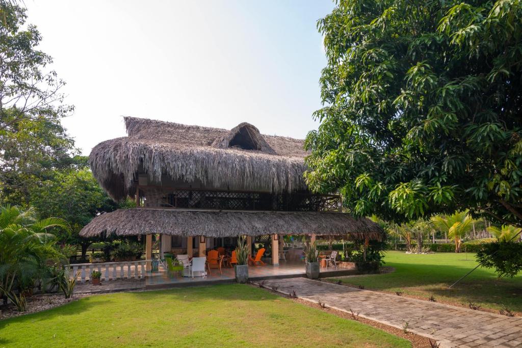 a house with a thatched roof with people in the yard at Casa Finca La Catalina in Montería