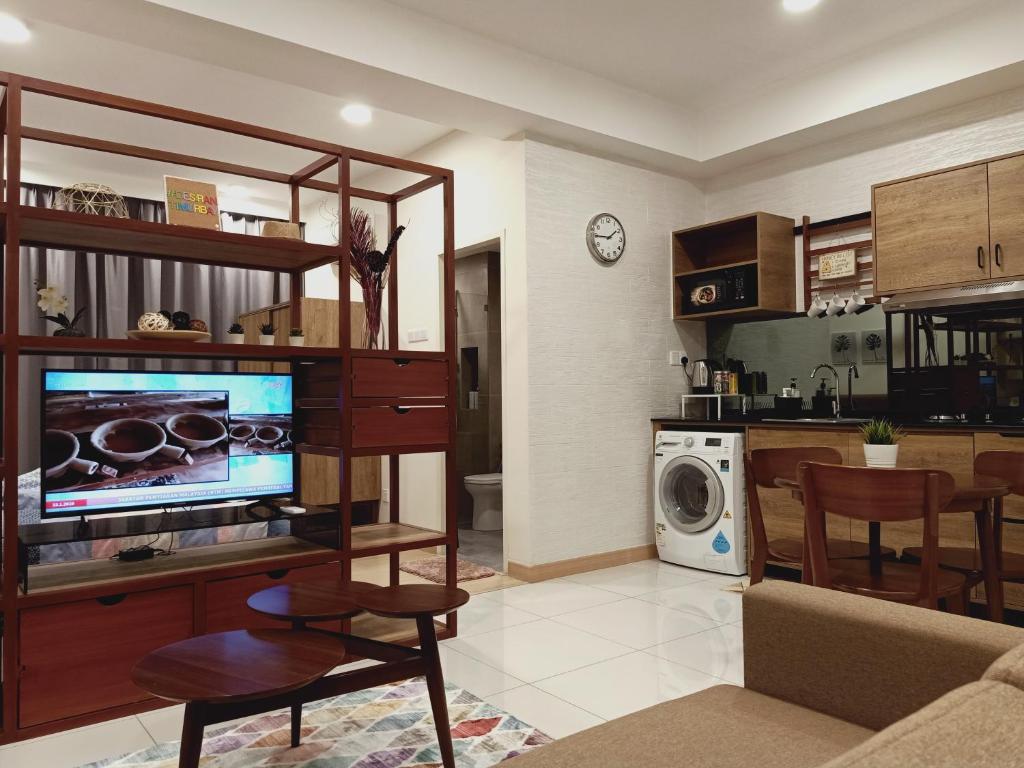 a living room with a flat screen tv and a kitchen at Desiran @ Timurbay - seafront studio apartment with WiFi in Kuantan