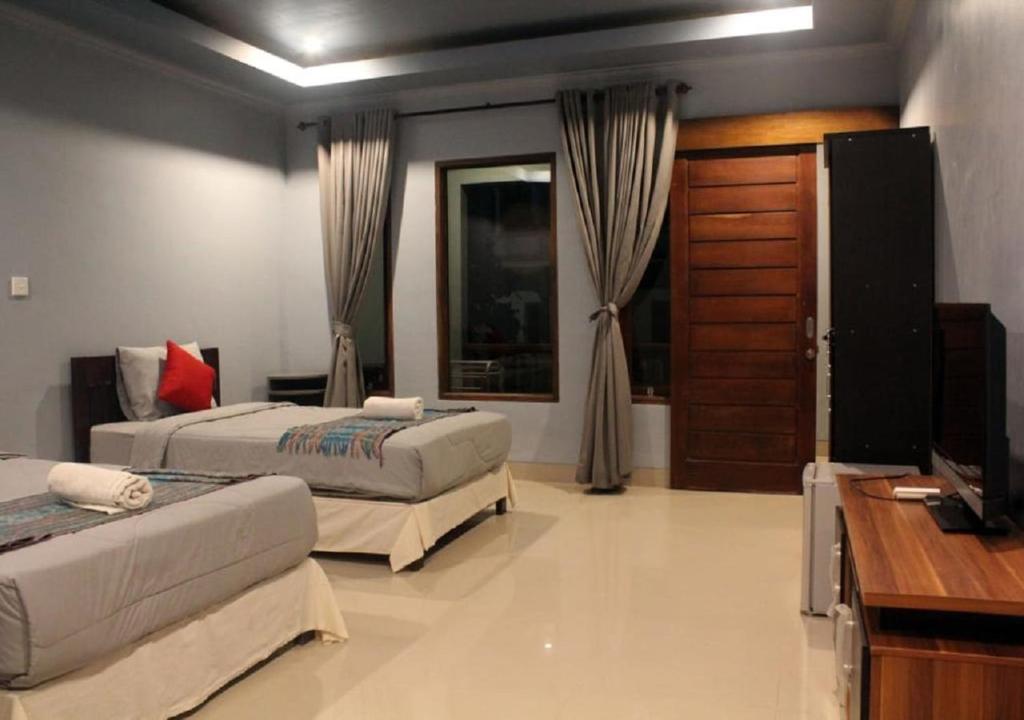 a bedroom with two beds and a television in it at Ridho Malik Hotel in Bumbang