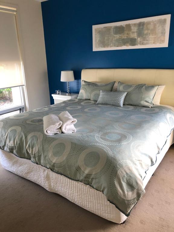 a bedroom with a large bed with blue walls at Residence On Robe in Robe