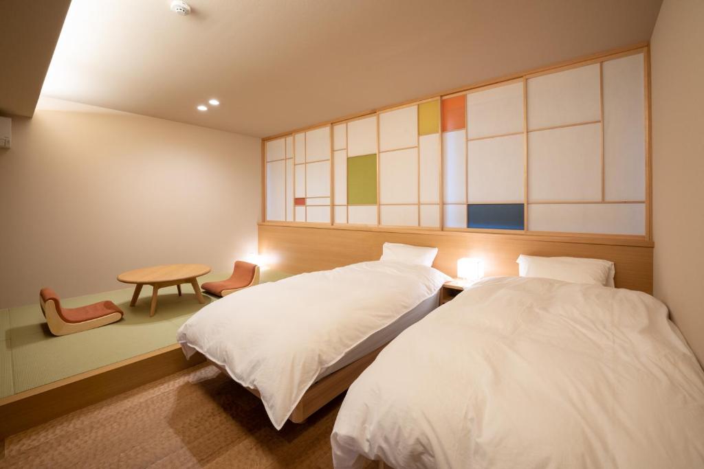 1 dormitorio con 2 camas, mesa y ventana en marutto Ishikawa en Kanazawa