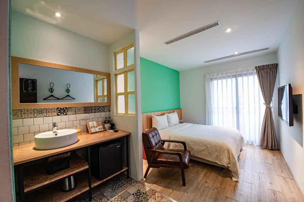 uma casa de banho com uma cama e um lavatório num quarto em 澎湖 就這兒旅居 em Magong