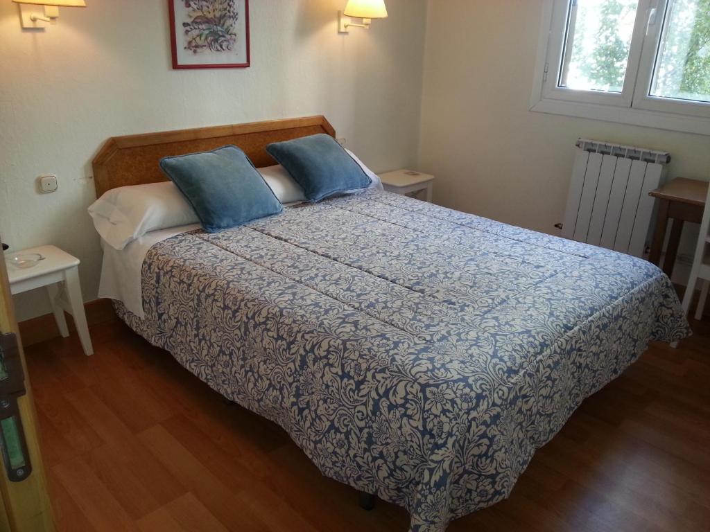 a bedroom with a large bed with blue pillows at Pensión Lizaso in Irún