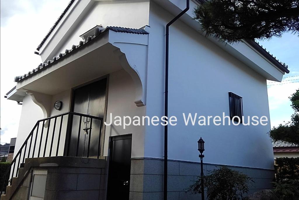 Ein weißes Haus mit einem Schild, das japanisches Lagerhaus liest. in der Unterkunft くまの蔵inn Warehouse in Shingu