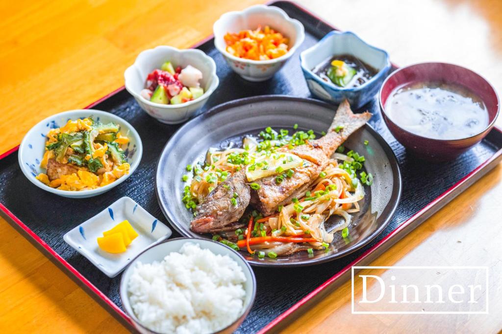 a tray of food with rice and meat and other dishes at kamekamehouse in Tokashiki
