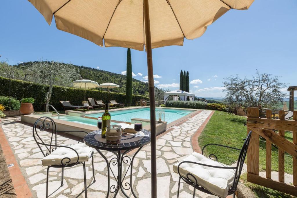 einen Tisch mit einem Sonnenschirm neben einem Pool in der Unterkunft Villa Manuela in Luiano