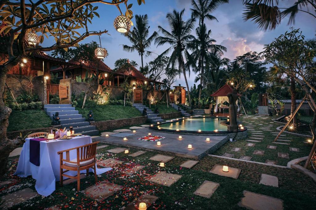 un complejo con piscina, mesa y luces en KERAMAN SUITE UBUD, en Ubud
