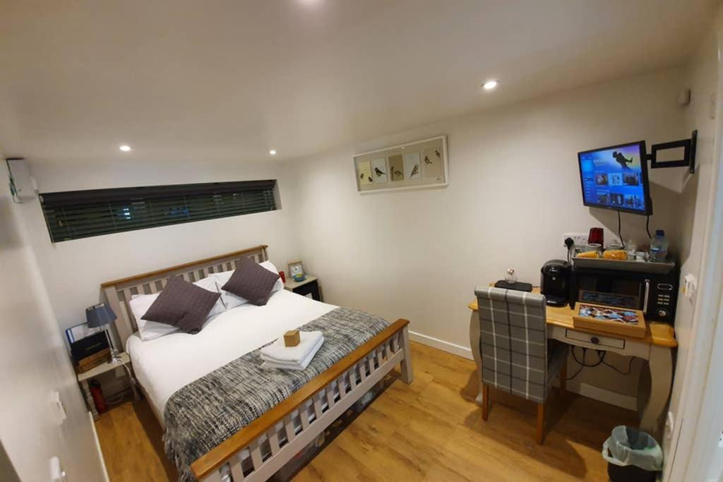 a bedroom with a bed and a desk with a television at Annex in Chippenham with Parking and WIFI in Chippenham