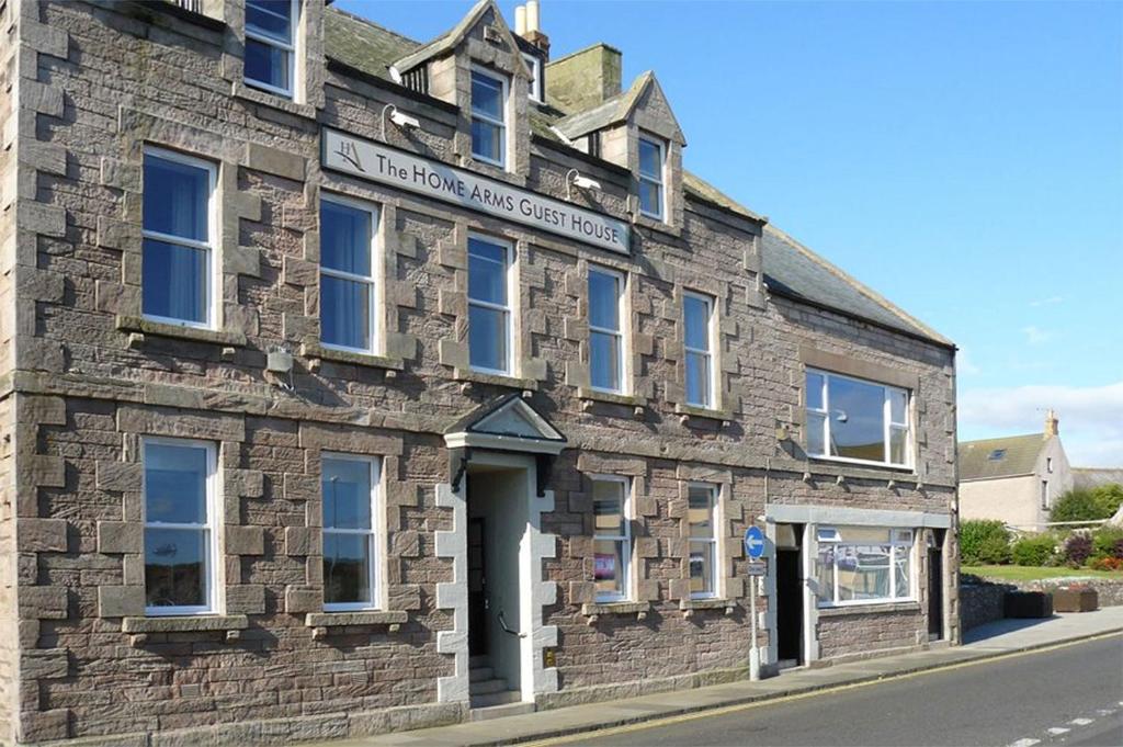 un antiguo edificio de piedra al lado de una calle en The Home Arms Guesthouse, en Eyemouth