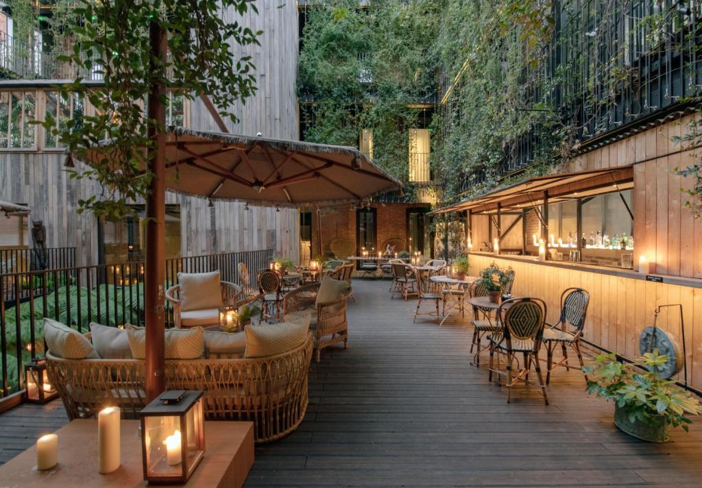 un patio con mesas, sillas y una sombrilla en The Mandrake, en Londres