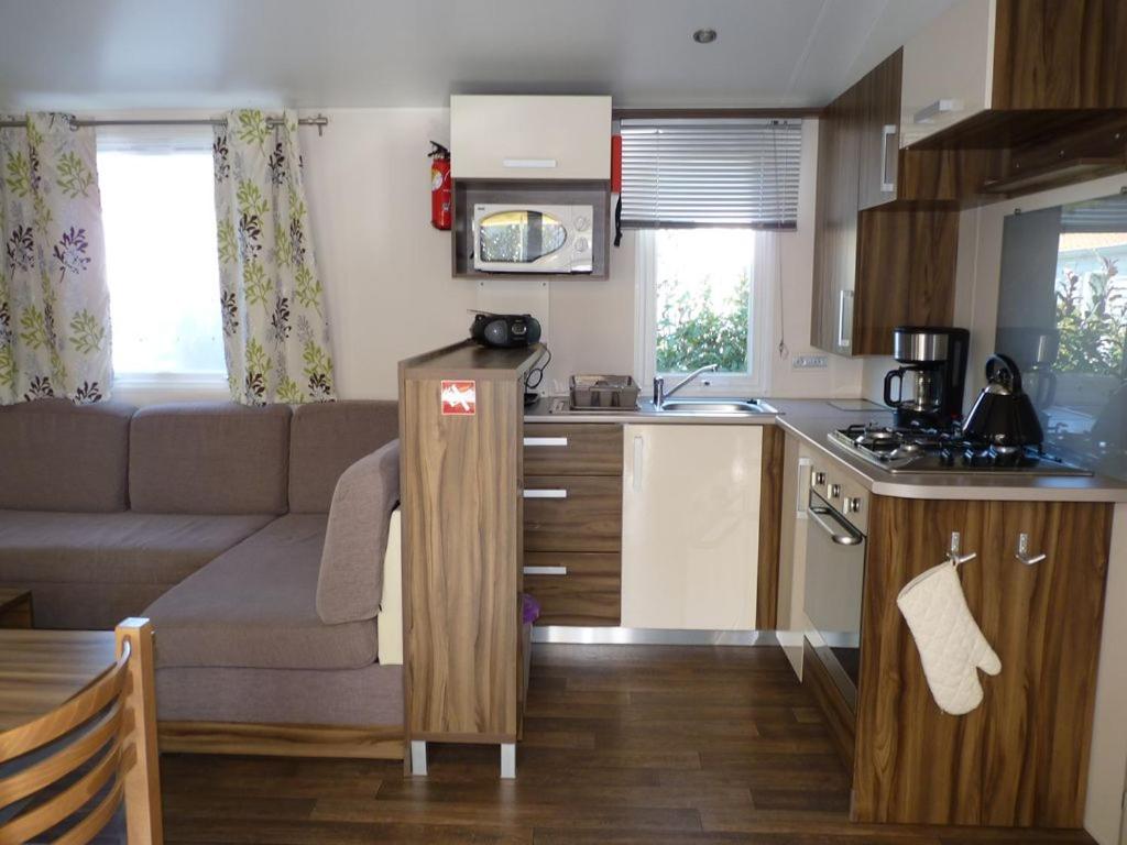 cocina y sala de estar con sofá en MOBIL HOME - 6 Pers - LES CHARMETTES ****, en Les Mathes