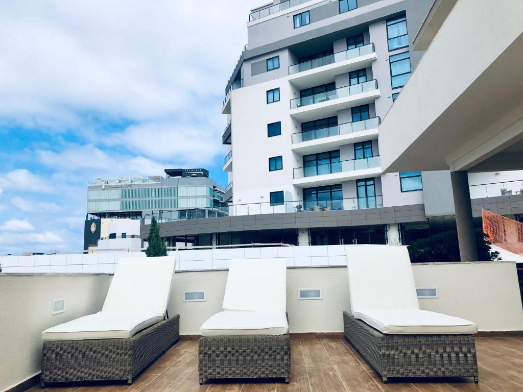 a balcony with white chairs and a tall building at Modern Luxury villa in St. Julians in St Julian's